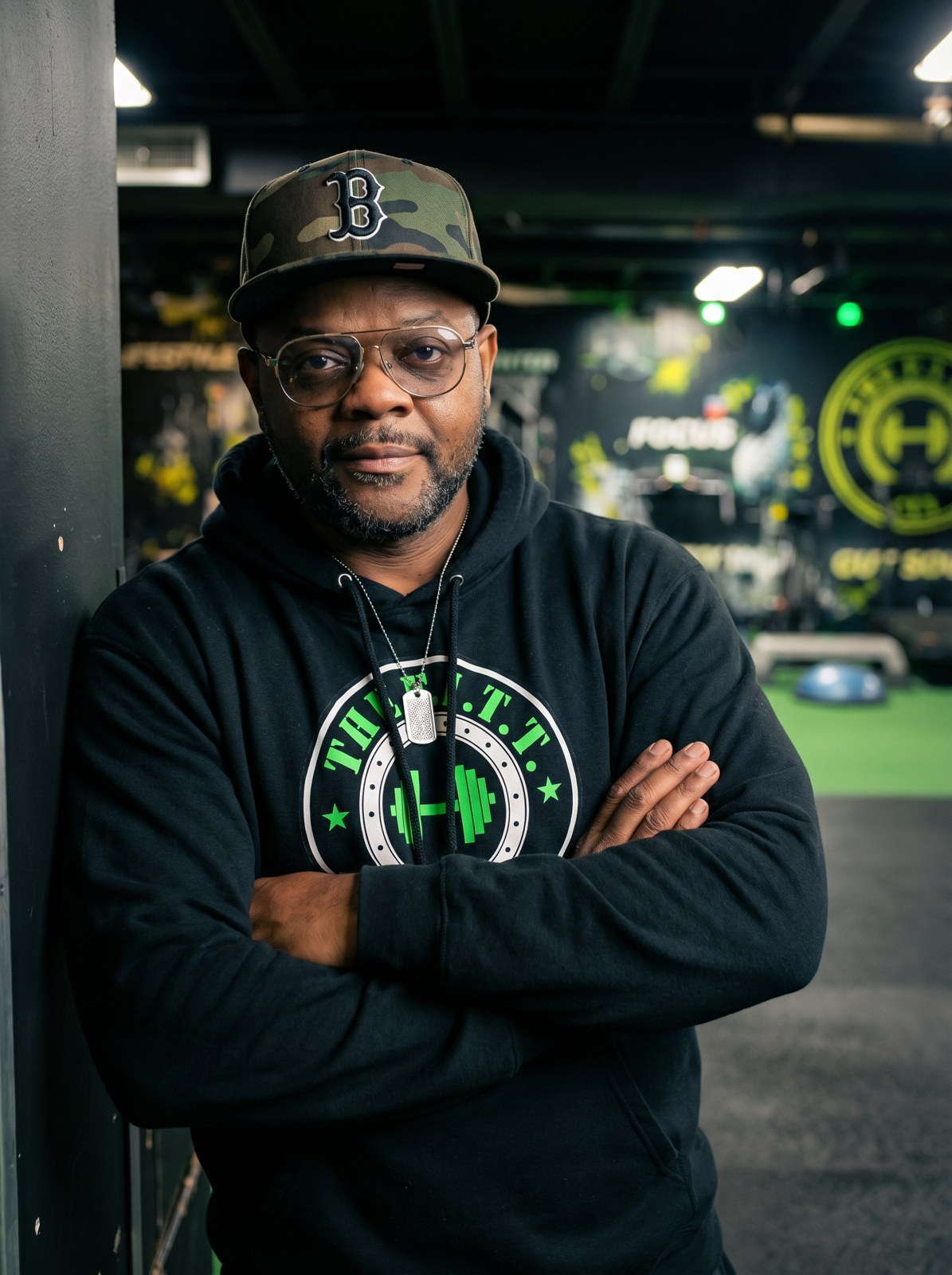 Dre Thomas standing in The F.I.T.T. PIT, arms crossed, in a gym hoodie